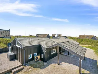 a tiny house with a deck and a playground at Holiday Home Dijana - 150m from the sea by Interhome in Saltum