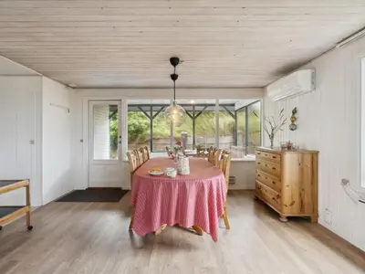a dining room with a table and chairs and windows at Holiday Home Aghe - 250m from the sea by Interhome in Saltum