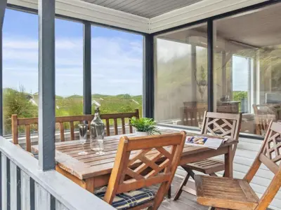 a screened in porch with a wooden table and chairs at Holiday Home Aghe - 250m from the sea by Interhome in Saltum