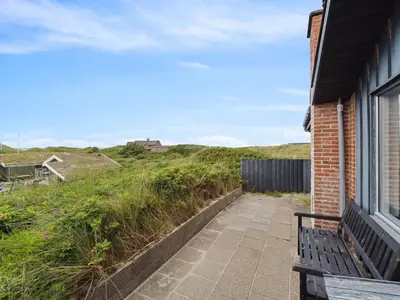 a bench sitting next to a building with a grassy hill at Holiday Home Aghe - 250m from the sea by Interhome in Saltum