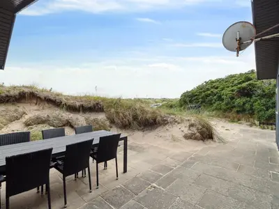 a table and chairs on a patio with a view of the beach at Holiday Home Aghe - 250m from the sea by Interhome in Saltum