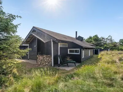 a black house with a bench in front of it at Holiday Home Allida - 800m from the sea by Interhome in Saltum