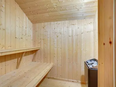 a wooden sauna with a bench and a trash can at Holiday Home Alhed - 650m from the sea by Interhome in Saltum