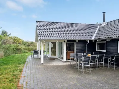 a house with a patio with a table and chairs at Holiday Home Alhed - 650m from the sea by Interhome in Saltum