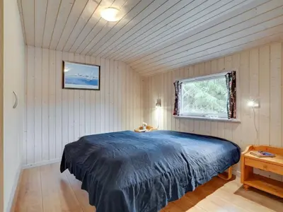 a bedroom with a blue bed in a room with a window at Holiday Home Alhed - 650m from the sea by Interhome in Saltum