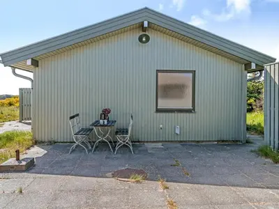 a green building with two chairs and a table at Holiday Home Ehawee - 350m from the sea by Interhome in Saltum
