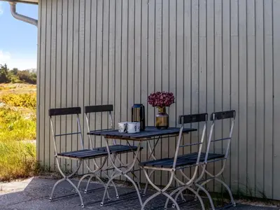 a table with two chairs and a vase of flowers at Holiday Home Ehawee - 350m from the sea by Interhome in Saltum