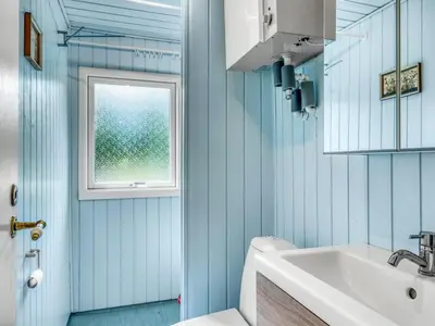 a bathroom with blue walls and a sink and a window at Holiday Home Jorek - 1-3km from the sea by Interhome in Saltum