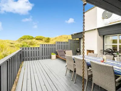 a porch with a swing and a table and chairs at Holiday Home Rosemari - 260m from the sea by Interhome in Saltum