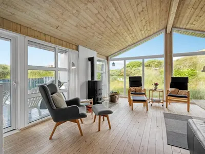 a living room with a couch and chairs and windows at Holiday Home Rosemari - 260m from the sea by Interhome in Saltum