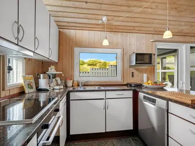a kitchen with white cabinets and a window at Holiday Home Rosemari - 260m from the sea by Interhome in Saltum