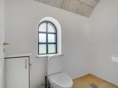 a bathroom with a white toilet and a window at Holiday Home Iben - 2-3km from the sea by Interhome in Saltum