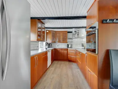 a kitchen with wooden cabinets and white appliances at Holiday Home Iben - 2-3km from the sea by Interhome in Saltum