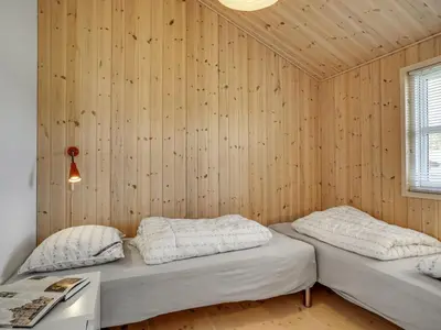 two beds in a room with wooden walls at Holiday Home Frerich - 1-5km from the sea by Interhome in Saltum