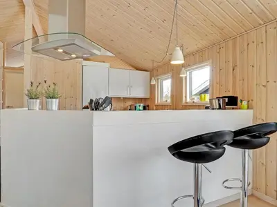 a kitchen with a white counter and two black stools at Holiday Home Frerich - 1-5km from the sea by Interhome in Saltum
