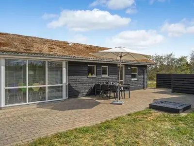 a patio with a table and an umbrella at Holiday Home Frerich - 1-5km from the sea by Interhome in Saltum