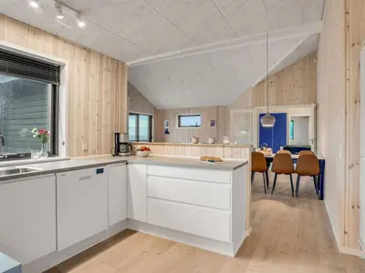 a kitchen with white cabinets and a dining room at Holiday Home Carla - 1-5km from the sea by Interhome in Saltum