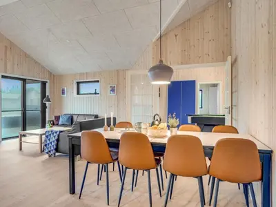 a dining room and living room with a table and chairs at Holiday Home Carla - 1-5km from the sea by Interhome in Saltum
