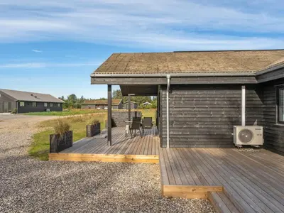 a house with a wooden deck with a roof at Holiday Home Carla - 1-5km from the sea by Interhome in Saltum
