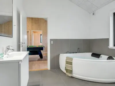 a large white bathroom with a tub and a sink at Holiday Home Carla - 1-5km from the sea by Interhome in Saltum