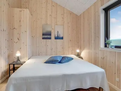 a bedroom with a white bed and a window at Holiday Home Carla - 1-5km from the sea by Interhome in Saltum