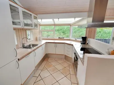 a kitchen with white cabinets and a large window at Holiday Home Hadar - 100m from the sea by Interhome in Saltum