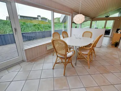 a dining room with a table and chairs and windows at Holiday Home Hadar - 100m from the sea by Interhome in Saltum