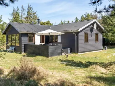 a small house with an umbrella in a yard at Holiday Home Antoinetta - 900m from the sea by Interhome in Saltum