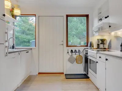 a kitchen with white cabinets and a large window at Holiday Home Antoinetta - 900m from the sea by Interhome in Saltum