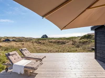 two lounge chairs and an umbrella on a patio at Holiday Home Felis - 200m from the sea by Interhome in Saltum