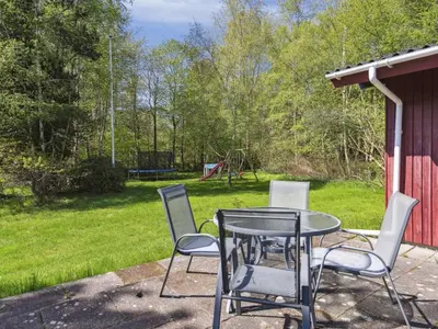 a table and chairs on a patio with a yard at Holiday Home Therbern - 1-7km from the sea by Interhome in Saltum