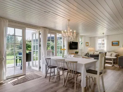 a dining room and living room with a table and chairs at Holiday Home Maunu - 1-2km from the sea by Interhome in Saltum