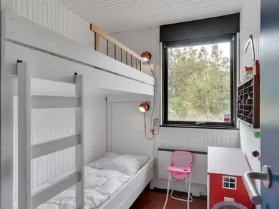 a small bedroom with a bunk bed and a pink chair at Holiday Home Kadife - 750m from the sea by Interhome in Saltum