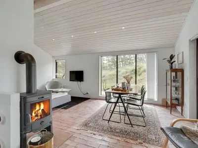 a living room with a fireplace and a table at Holiday Home Kadife - 750m from the sea by Interhome in Saltum
