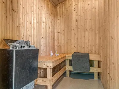 a wooden sauna with a bench and a chair at Holiday Home Nayati - 2km from the sea by Interhome in Saltum