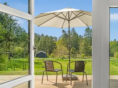 a patio with two chairs and an umbrella at Holiday Home Nayati - 2km from the sea by Interhome in Saltum