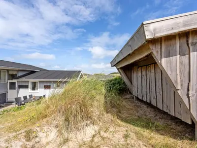a building on the side of a field next to a house at Holiday Home Kulle - 200m from the sea by Interhome in Saltum