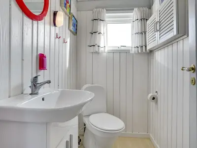 a white bathroom with a sink and a toilet at Holiday Home Kulle - 200m from the sea by Interhome in Saltum