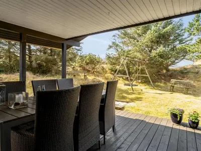 a deck with a table and chairs and a swing at Holiday Home Gerwer - 700m from the sea by Interhome in Saltum