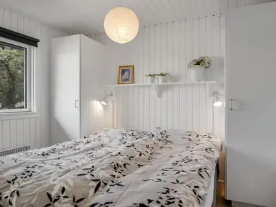 a white bedroom with a bed with a black and white comforter at Holiday Home Gerwer - 700m from the sea by Interhome in Saltum