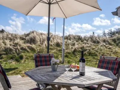 a picnic table with a bottle of wine and two glasses at Holiday Home Asser - 400m from the sea by Interhome in Saltum