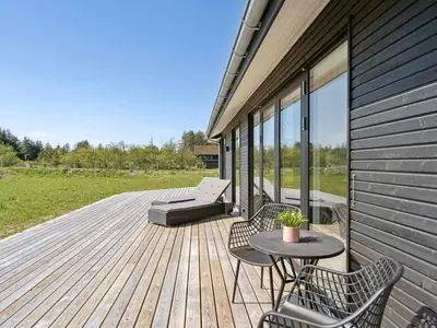a deck with a bench and a table and chairs at Holiday Home Fredrika - 1-5km from the sea by Interhome in Saltum