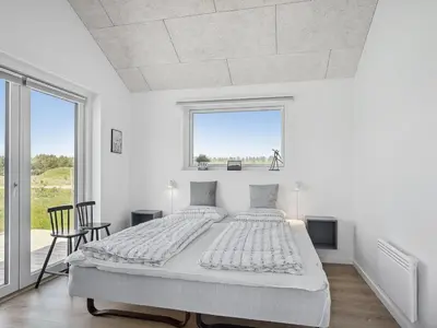 a white bedroom with a large bed and a window at Holiday Home Fredrika - 1-5km from the sea by Interhome in Saltum