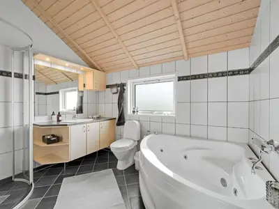 a bathroom with a tub and a toilet and a sink at Holiday Home Sochyeta - 150m from the sea by Interhome in Harboør