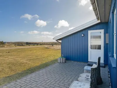 a blue building with a bench next to a field at Holiday Home Soyala - 400m from the sea by Interhome in Harboør