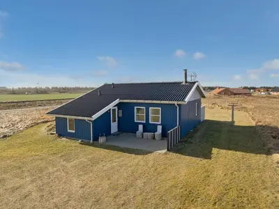 a blue house in the middle of a field at Holiday Home Soyala - 400m from the sea by Interhome in Harboør