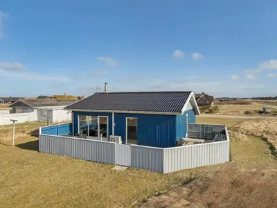 a blue house on top of a grass field at Holiday Home Soyala - 400m from the sea by Interhome in Harboør