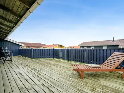 a wooden deck with a chair on top of it at Holiday Home Odmar - 300m from the sea by Interhome in Harboør