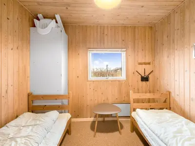 a room with two beds and a table and a window at Holiday Home Odmar - 300m from the sea by Interhome in Harboør