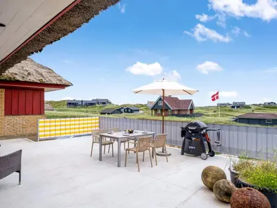 a patio with a table and an umbrella at Holiday Home Zora - 100m from the sea by Interhome in Harboør